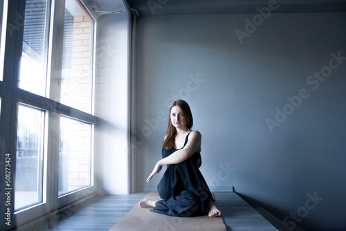 Принти на полотні Yoga a woman practices asanas in black clothes by the window