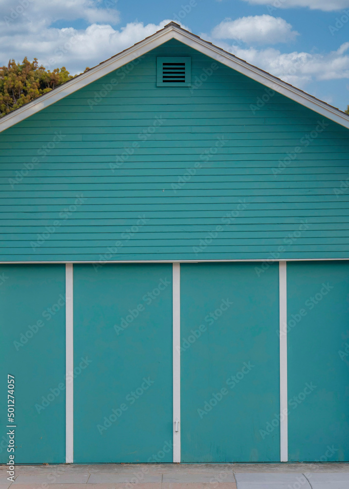 Vertical White puffy clouds Aqua blue detached garage exterior at Oceanside, California