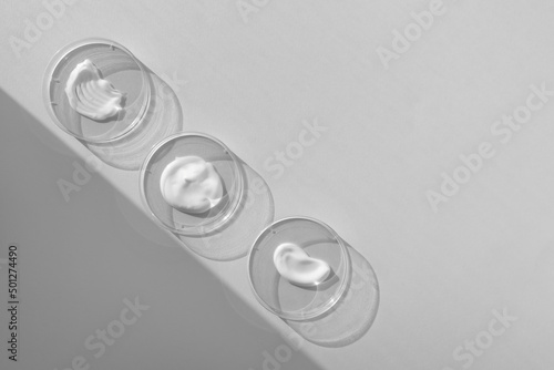White cream textures in Petri dishes on a gray background. Concept of cosmetics laboratory researches. Smear of skincare cosmetics product. Wellness and beauty concept. Soft focus