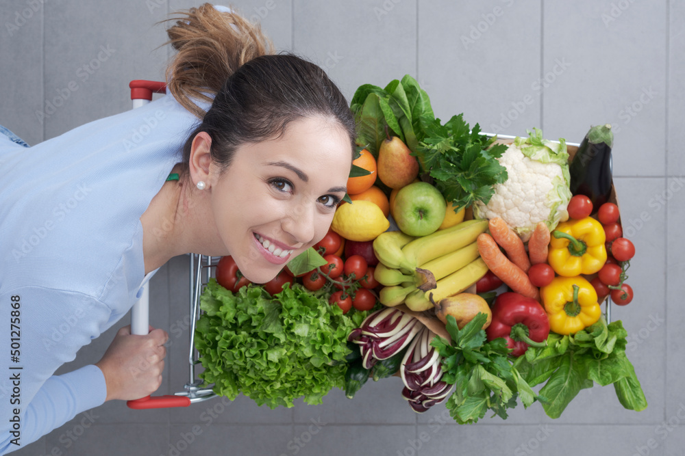 Happy woman pushing a trolley full of greens Happy woman pushing a trolley full of greens