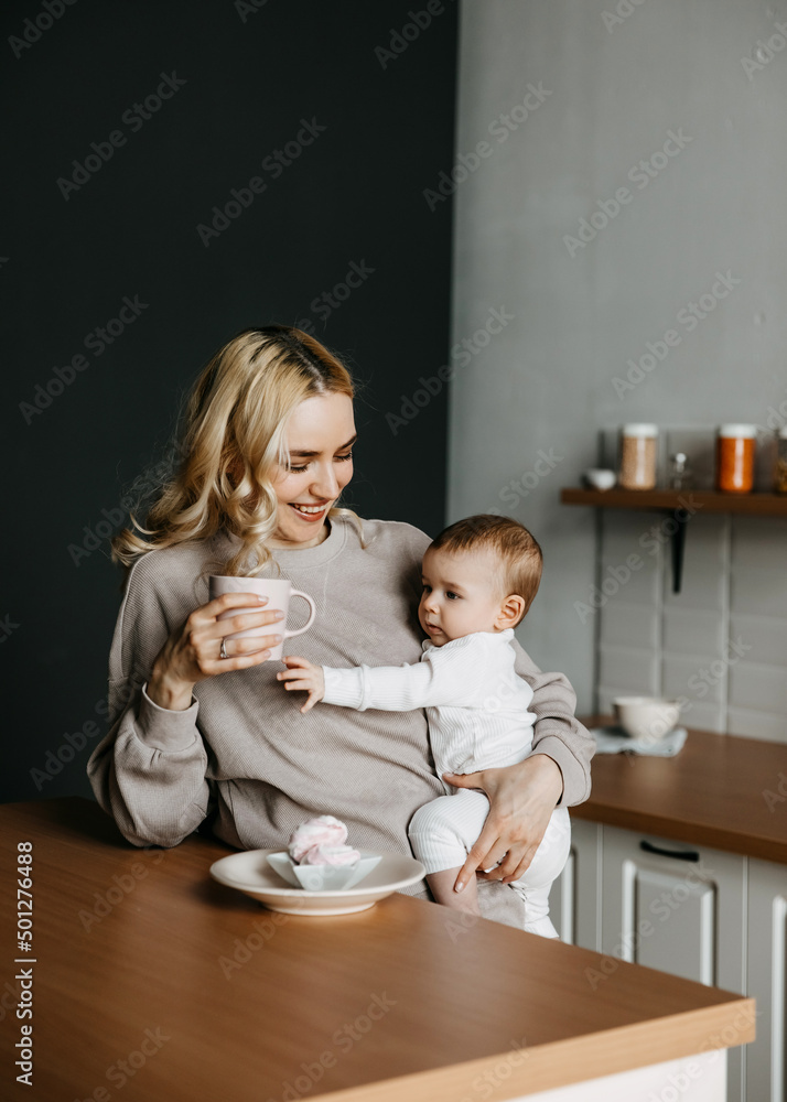 Mother and son at the kitchen wearing pajamas. Woman holding baby