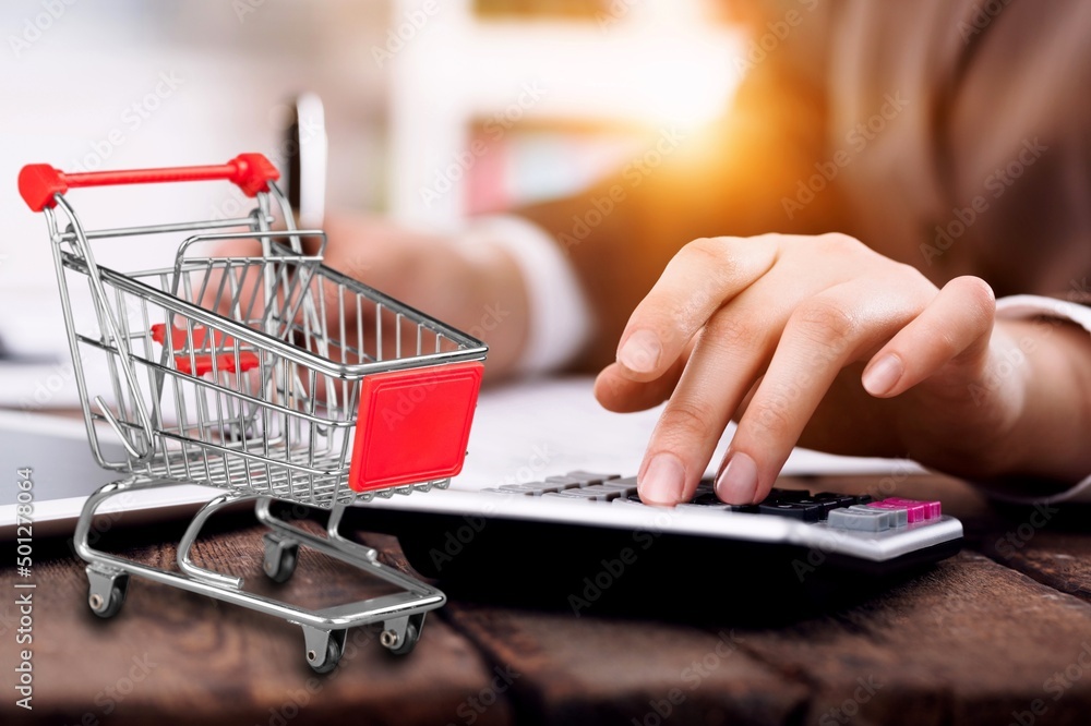 Shopping cart and man working on calculator with financial document. Financial crisis concept. Shopping cart and man working on calculator with financial document. Financial crisis concept.