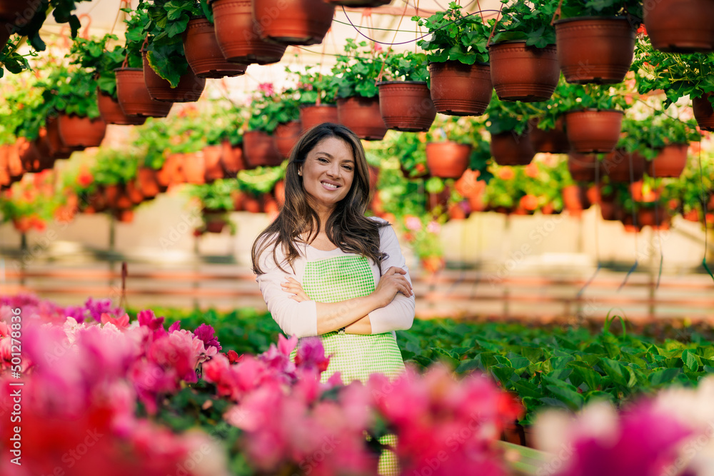 Fototapeta premium Portrait of a beautiful Caucasian woman in a working environment of a flower greenhouse.