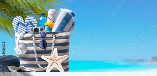 Fototapeta Naklejka Na Ścianę i Meble -  Beach bag with accessories and tropical beach