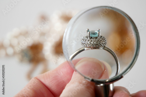 jeweler looking at ring with blue stone, jewerly inspect and verify, pawnshop concept, jewerly shop