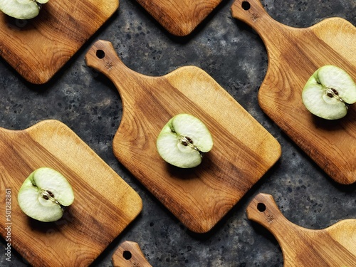Murais de parede Pattern of slice of green apple on wooden cutting board on black concrete background