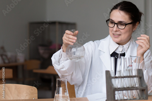 Woman in a white coat and glasses working in hemical or biologycal laboratory with samples in tubes photo