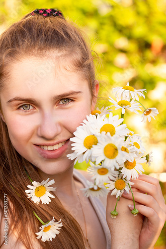 A beautiful young girl smiles at the camera and holds a bouquet of flowers