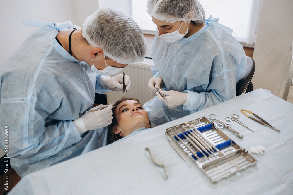 Obraz premium Team of surgeon in uniform perform operation on a patient at plastic surgery clinic