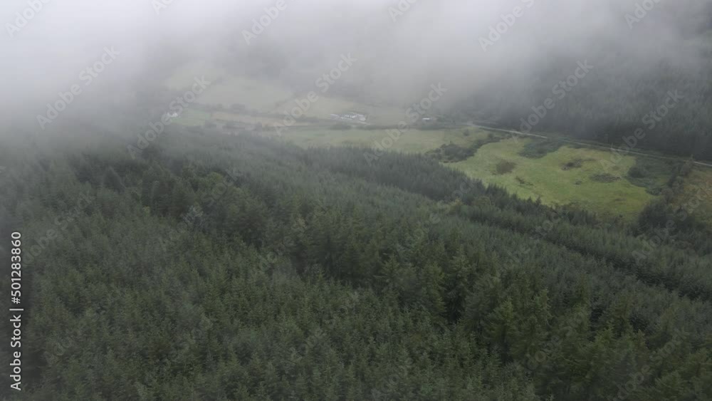 Drone shot emerging out of a cloud, revealing a green lush valley. Drone shot emerging out of a cloud, revealing a green lush valley.