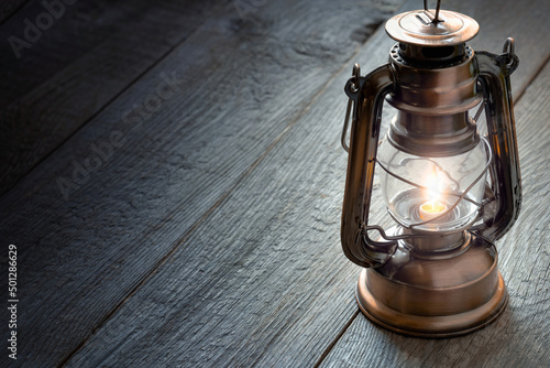 Fotografie an old portable lantern on a wooden table, a kerosene lamp illuminates the table
