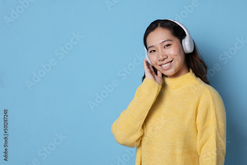 Portrait of a young asian woman with headphones smiling to the camera