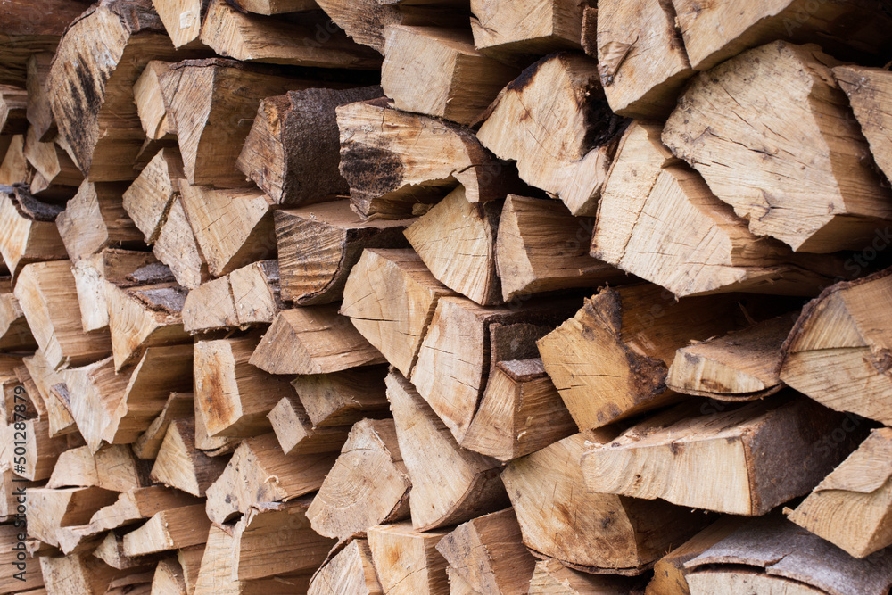 Fototapeta premium Fresh brown pile of tree stumps, woods structure. Wooden pattern background. Ecological heating, renewable energy sources. Ecological fuel. Sawmill, woodworking industry chopped firewood