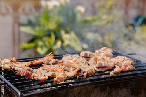 Man cooking pork chops on barbecue grill for an outdoor summer party. Smoke from the barbecue. Background of food.