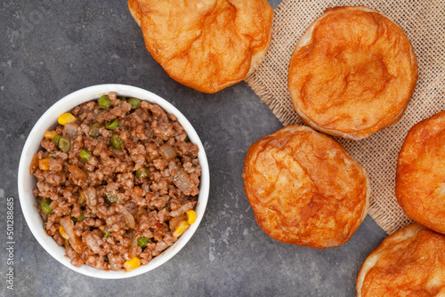 South African vetkoek, deep fried savory dough filled with saucy savory mince on mottled grey background with copy space

 photo