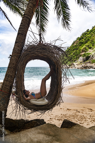 Young beautiful female model pose on the swing nest  at Nui Beach Phuket Thailand