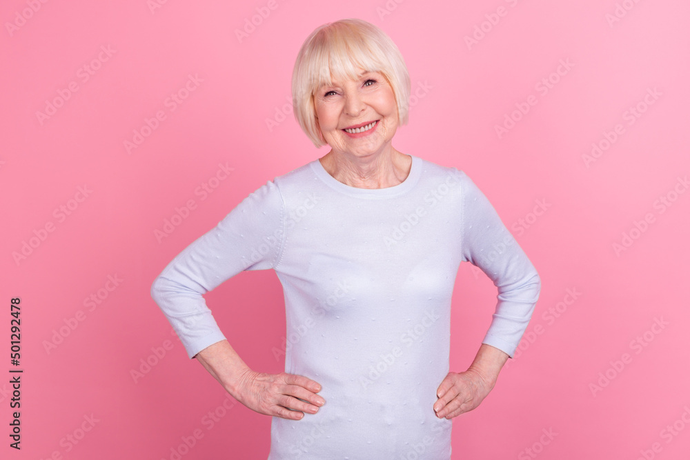 Photo of senior charming woman good mood hands on waist confident isolated over pink color background Photo of senior charming woman good mood hands on waist confident isolated over pink color background