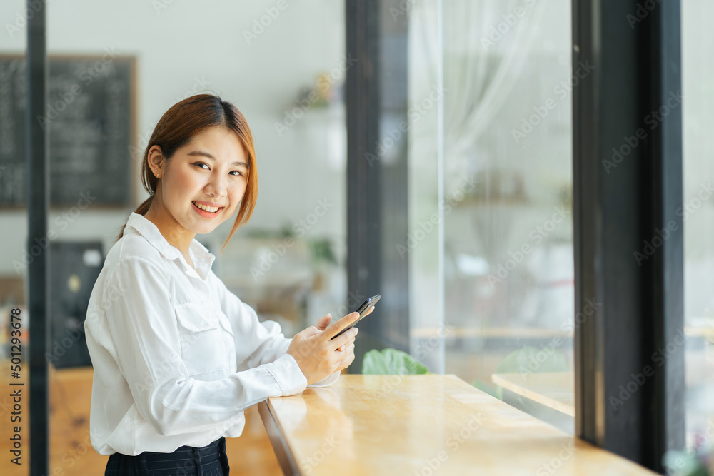 Asian businesswoman in casual office wear is happy and cheerful while communicating with her smartphone.