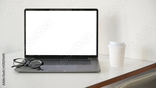Notebook laptop computer white screen mockup on white office desk.
