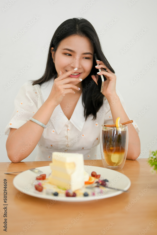 Woman waiting her friends in the cafe, enjoy talking on the phone