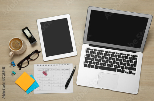 Modern gadgets  cup of coffee and office stationery on wooden table  flat lay. Distance learning