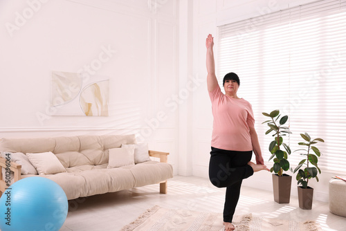 Fototapeta Naklejka Na Ścianę i Meble -  Overweight mature woman practicing yoga at home