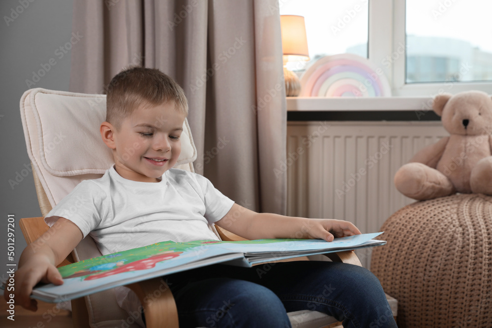 Cute little boy reading book at home, space for text Cute little boy reading book at home, space for text