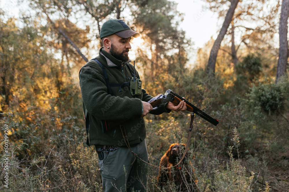 Fototapeta premium Hunter opening his hunting shotgun and watching cartridge in nature