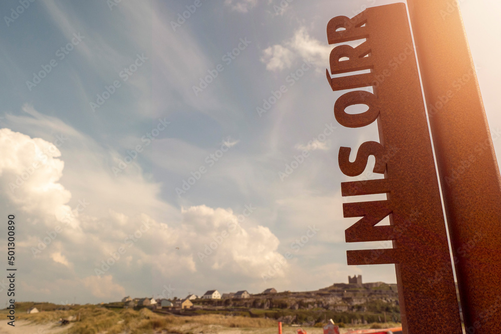 Metal sign with sign Inisheer in Irish language. Warm sunny day. Popular travel and tourism area. Nobody. Aran Islands, county Galaway, Ireland. Metal sign with sign Inisheer in Irish language. Warm sunny day. Popular travel and tourism area. Nobody. Aran Islands, county Galaway, Ireland.