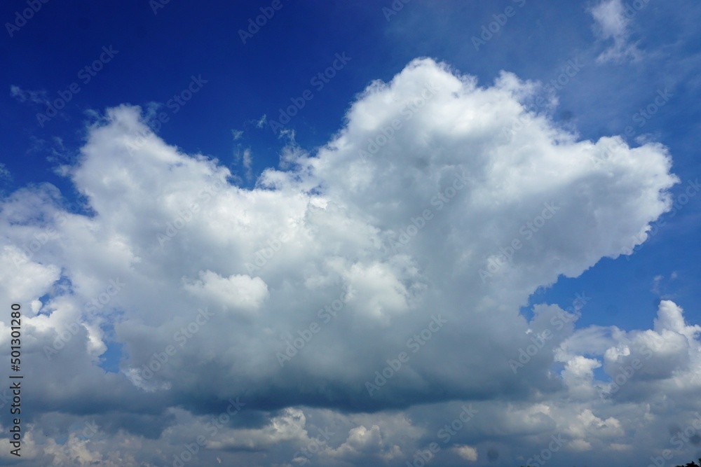 Obraz premium Starkes weißes Wolkengebilde am blauen Himmel bei Sonne 