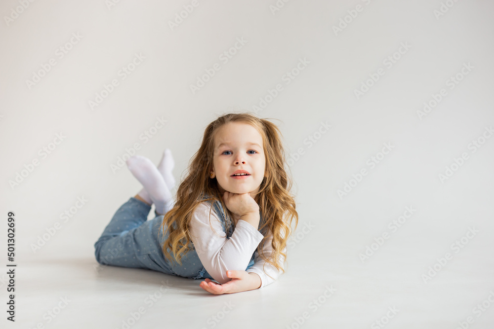 beautiful cute baby girl lies on her stomach and looks into the camera with slightly wavy hair. pretty Baby. happy childhood. beautiful cute baby girl lies on her stomach and looks into the camera with slightly wavy hair. pretty Baby. happy childhood.