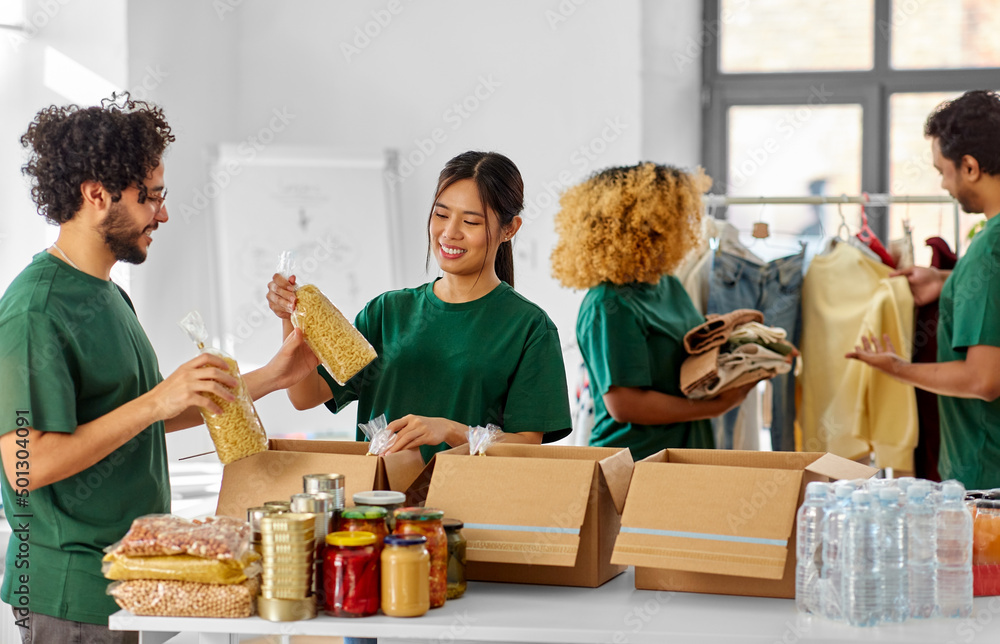 © Syda Productions - charity, donation and volunteering concept - international group of happy smiling volunteers packing food and clothes in boxes at distribution or refugee assistance center