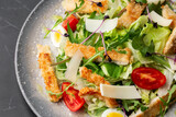 A Caesar salad with grilled chicken breasts, lettuce, croutons, eggs, cherry tomatoes, dressed with Parmesan cheese and sauce.