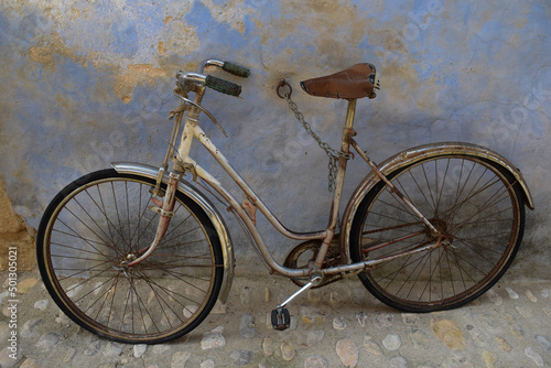 old and rusty vicicleta in tied to a blue wall photo