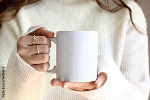 Murais de parede Girl is holding white mug in hands. Blank 11 oz ceramic cup