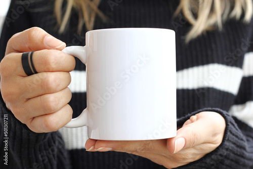 Girl is holding white cup in hands. 11 oz mug in woman's hands. photo
