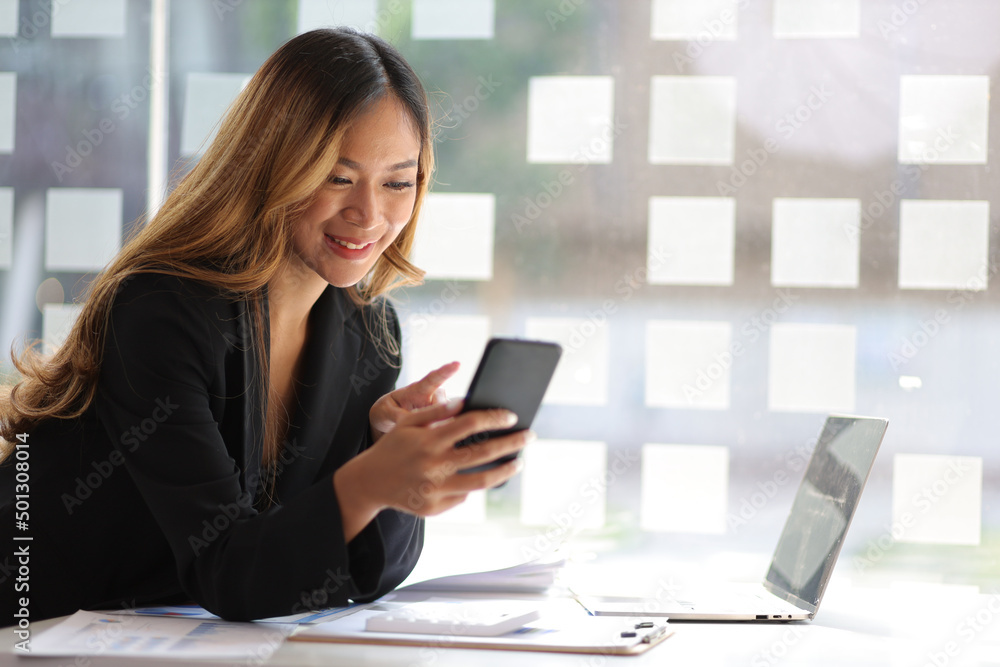 Happy businesswoman using mobile phone while working at office and messaging with smartphone. Happy businesswoman using mobile phone while working at office and messaging with smartphone.