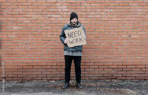 Fotografie Homeless holds piece of cardboard with inscription Need Work