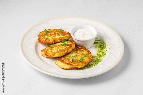 Potato fritters, latkes, draniki, hash browns. Vegetable pancakes on a plate. Close up Draniki, wizards of potatoes with sour cream. photo