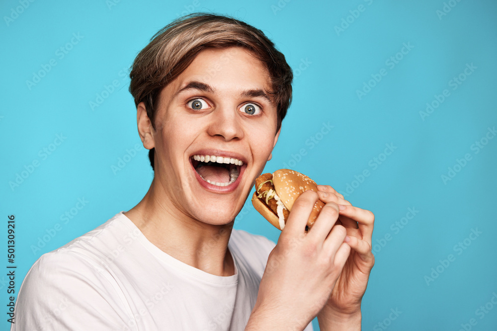 Very hungry young man holding tasty hamburger Very hungry young man holding tasty hamburger