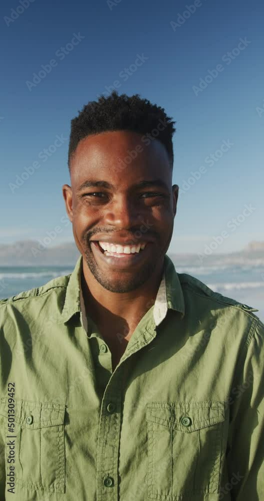 Vertical video of happy arican american man smiling at camera on beach Vertical video of happy arican american man smiling at camera on beach