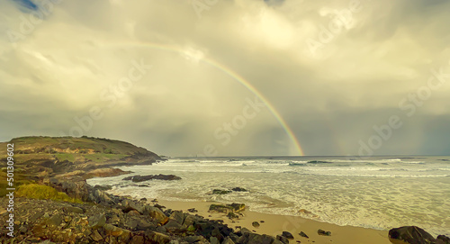 Landscape view of rainbow over the ocean view on overcast day.