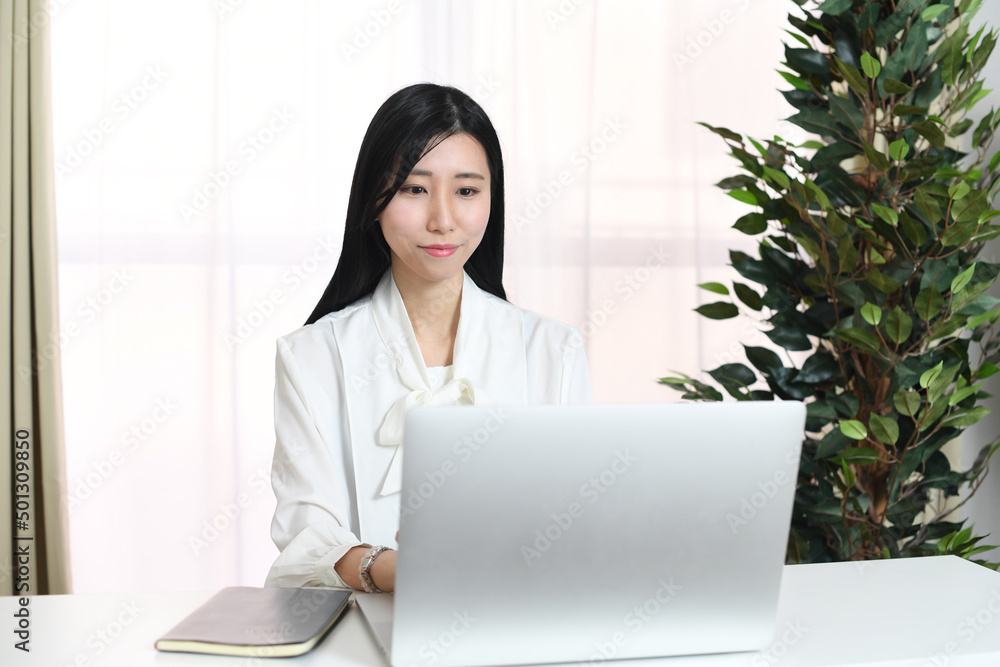 笑顔でパソコン操作するアジア人の女性