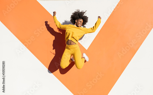 Smiling young woman jumping on sunny day photo