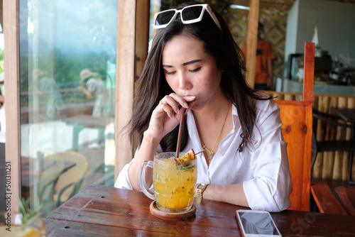 Young beautiful asian woman drinking passion fruit juice at the cafe
