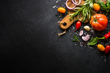 Food cooking background on black stone table. Fresh vegetables, herbs and spices. Top view with copy space.