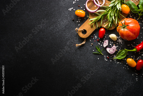 Food cooking background on black stone table. Fresh vegetables, herbs and spices. Top view with copy space. photo