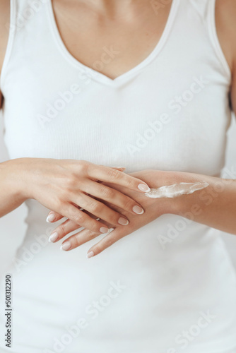 Closeup of female hands applying hand cream.Hand Skin Care. Girl hands with french manicure.