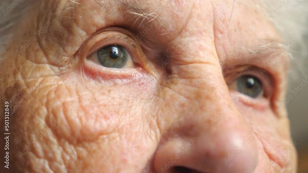 Portrait of elderly woman watching pensive to something. Close up of female face with wrinkles. Grandmother looking calmly into distance showing emotions of sad or loneliness. Detail view Slow motion Portrait of elderly woman watching pensive to something. Close up of female face with wrinkles. Grandmother looking calmly into distance showing emotions of sad or loneliness. Detail view Slow motion