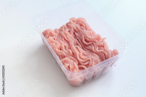 Minced meat in a transparent plastic container. Fresh pork minced meat, on white background.